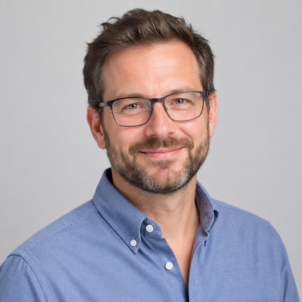 Studio portrait of a man with glasses smiling